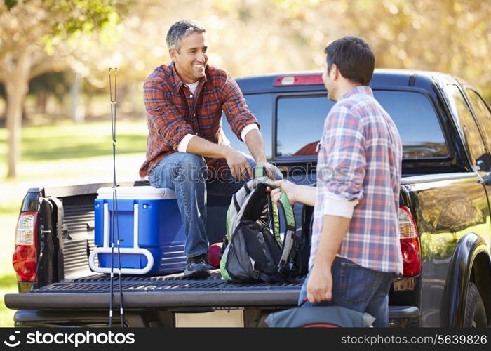 Two Men Unpacking Pick Up Truck On Camping Holiday