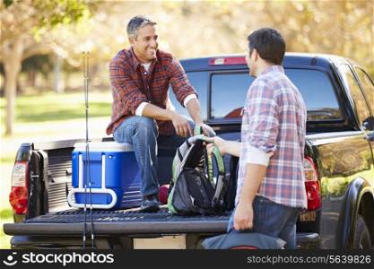 Two Men Unpacking Pick Up Truck On Camping Holiday