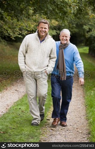 Two men walking on path outdoors smiling (selective focus)