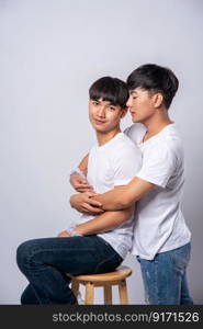 Two men who love each other hug and sit on a chair.