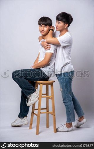 Two men who love each other hug and sit on a chair.