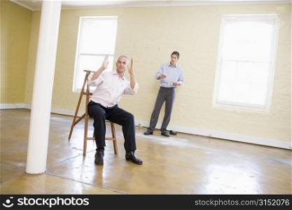 Two men with ladder in empty space making plans for room