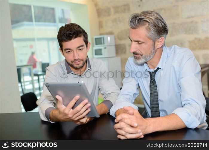two men with modern technology at a work canteen