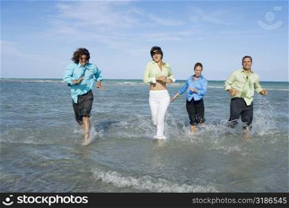 Two mid adult couples running on the beach