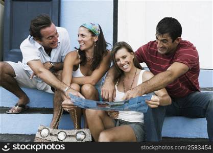Two mid adult couples sitting on steps and smiling