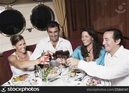 Two mid adult couples toasting with wine glasses and smiling