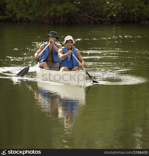 Two mid adult men canoeing