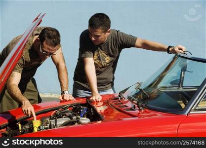 Two mid adult men examining a car engine, Miami, Florida, USA