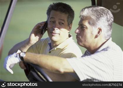 Two mid adult men in a golf cart