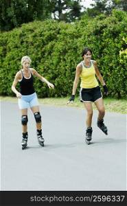 Two mid adult women inline skating