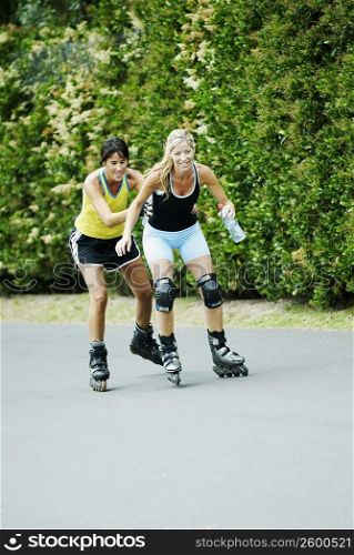 Two mid adult women inline skating