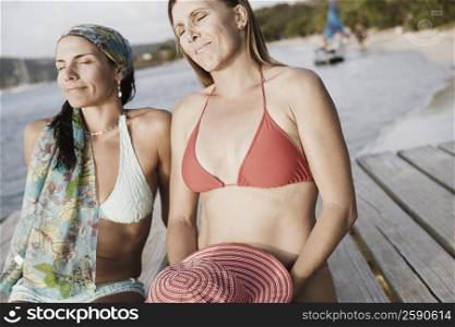 Two mid adult women sitting on a pier
