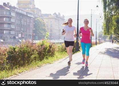 two middle aged female friends jogging have morning workout with sunrise in background