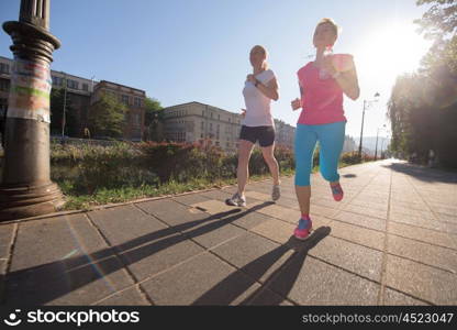 two middle aged female friends jogging have morning workout with sunrise in background