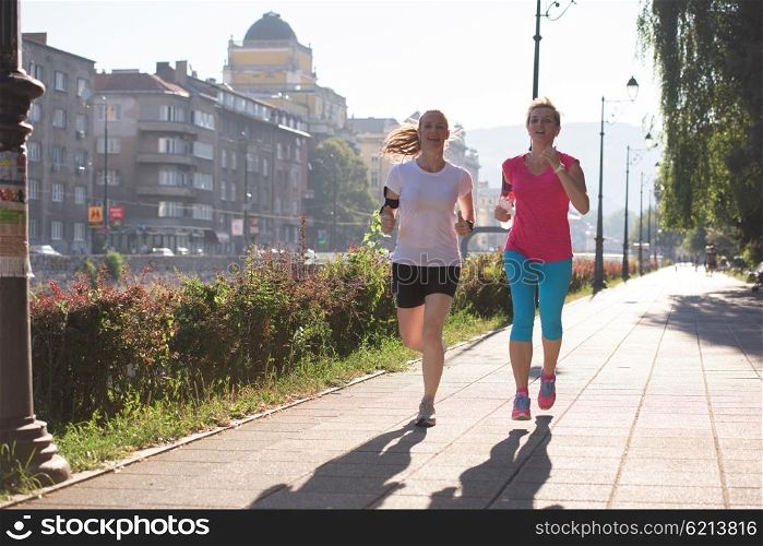 two middle aged female friends jogging have morning workout with sunrise in background