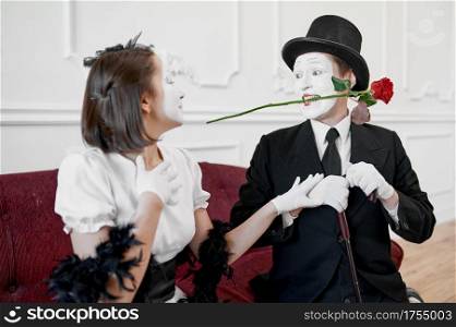 Two mime artists, love couple, scene with rose. Pantomime theater, parody comedian, positive emotion, humour performance, funny face mimic and grimace. Two mime artists, love couple, scene with rose