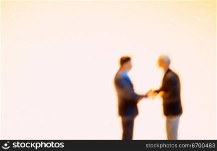 Two miniature male figures shaking hands
