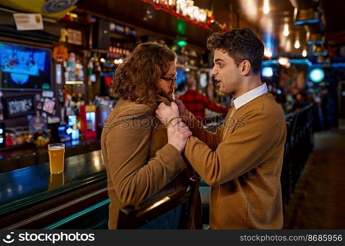 Two misunderstanding friends quarrelling at sport bar. Angry emotional man shouting pulling guy by jacket collar. Mates conflict and fight concept. Two misunderstanding friends quarrelling at sport bar