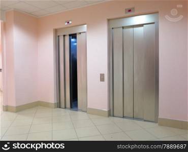 two modern lifts one with opened and another with closed doors