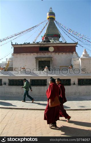 Two monks walk near stupa Bodnath in Kathmandu, Nepal