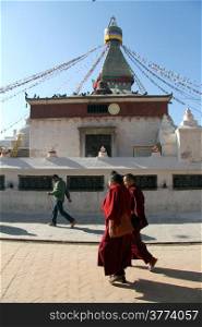 Two monks walk near stupa Bodnath in Kathmandu, Nepal