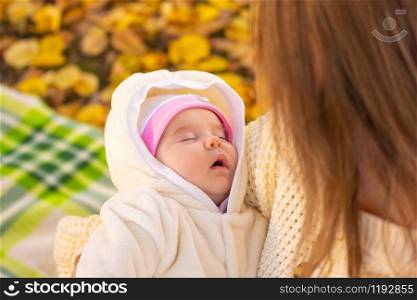 Two-month-old baby sleeps in mom&rsquo;s arms