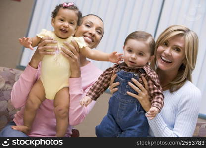 Two mothers holding two IVF children smiling