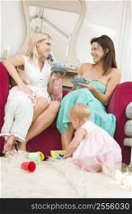 Two mothers in living room with babies and coffee smiling