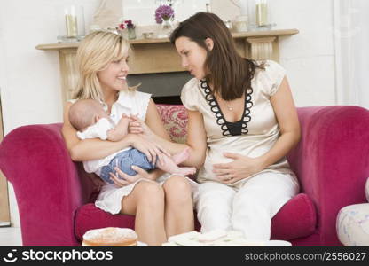 Two mothers in living room with baby and cake smiling