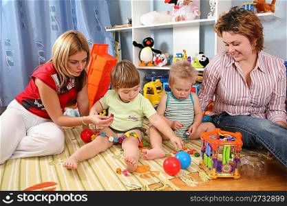 two mothers play with children in playroom
