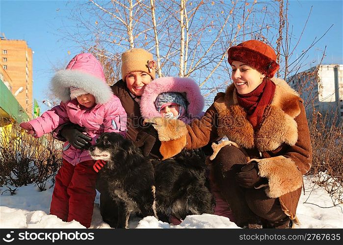 two mothers with children and dog on street in winter