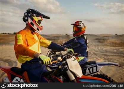 Two motocross MX riders talking together before speed racing. Extreme sport recreational pursuit. Two motocross MX riders talking before racing