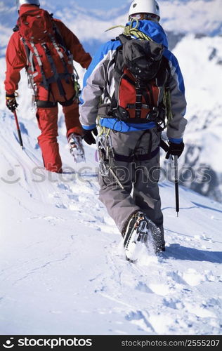 Two mountain climbers walking in snow (selective focus)