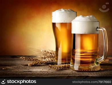 Two mugs of beer and wheat on a wooden table