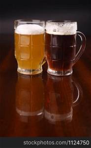 Two mugs of beer over a dark background
