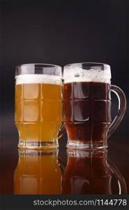 Two mugs of beer over a dark background