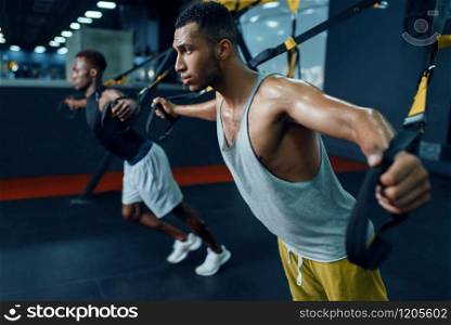 Two muscular athletes in sportswear at stretching exercise machine on training in gym. Workout in sport club, healthy lifestyle. Two athletes at stretching exercise machine