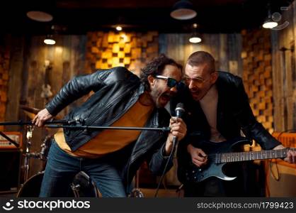 Two musicians at microphone, music performing on stage. Rock band performance or repetition in garage, man with musical instrument, live sound performers. Two musicians at microphone, rock band