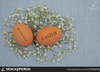 two natural colored eggs with the words happy easter lying on a bed of on gypsophila