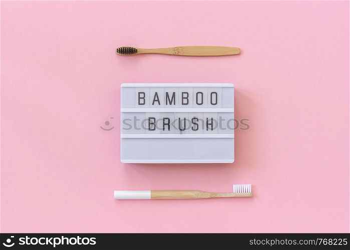 Two natural eco-friendly bamboo brushes with white and black bristles and lightbox text Bamboo brush on paper pink background. Top view Flat lay Template Concept. Two natural eco-friendly bamboo brushes with white and black bristles and lightbox text Bamboo brush on pink paper background. Top view Flat lay Template Concept