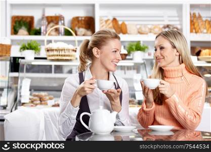 Two nice girls drink tea in cafe
