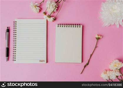 two notebook, pen and flower on pink background