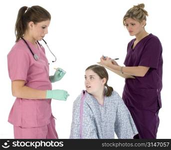 Two nurses and teen patient. Patient girl in hospital gown looking afraid at shot.