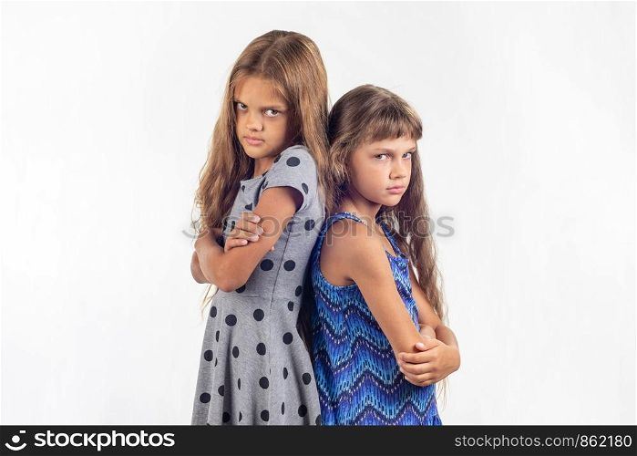 Two offended girls stand with their backs to each other