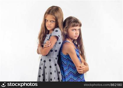 Two offended girls stand with their backs to each other