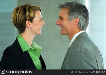 Two office colleagues smiling at each other.