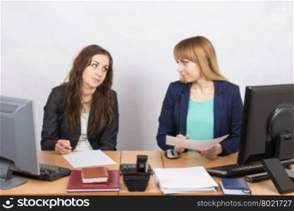 Two office employee sitting at a desk and a hostile look at each other