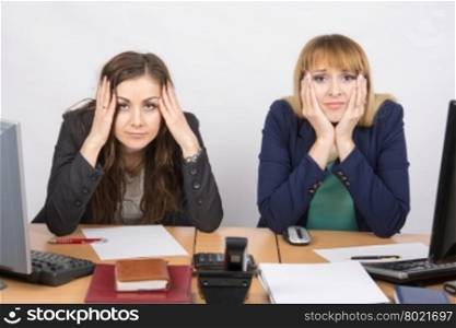 Two office employee sitting with depressed and frightened look