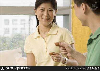 Two office workers holding tea cups and smiling