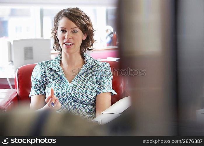 Two office workers sitting on sofas in office focus on woman